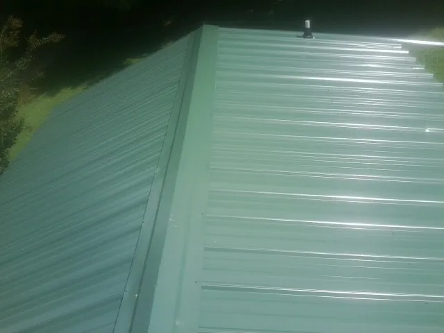 New green metal panels meeting at the ridge of a roof — Flat Roof Repair work by our crew in Toronto