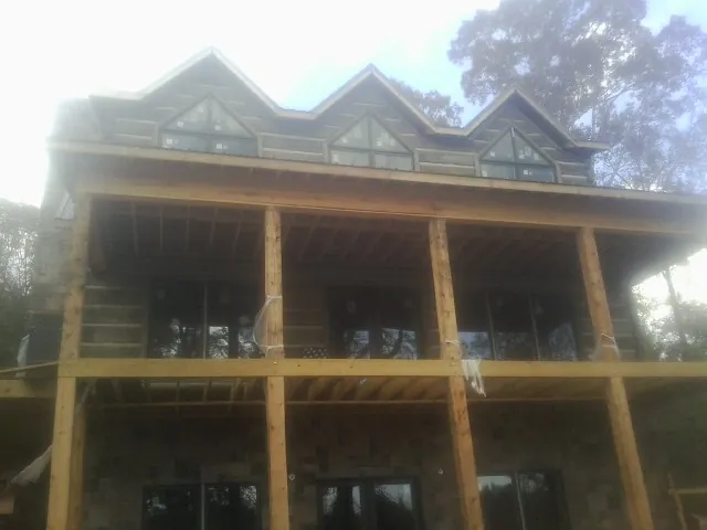 Dormers and porch framing on a large log home under construction — Roof Coating work by our crew in Toronto