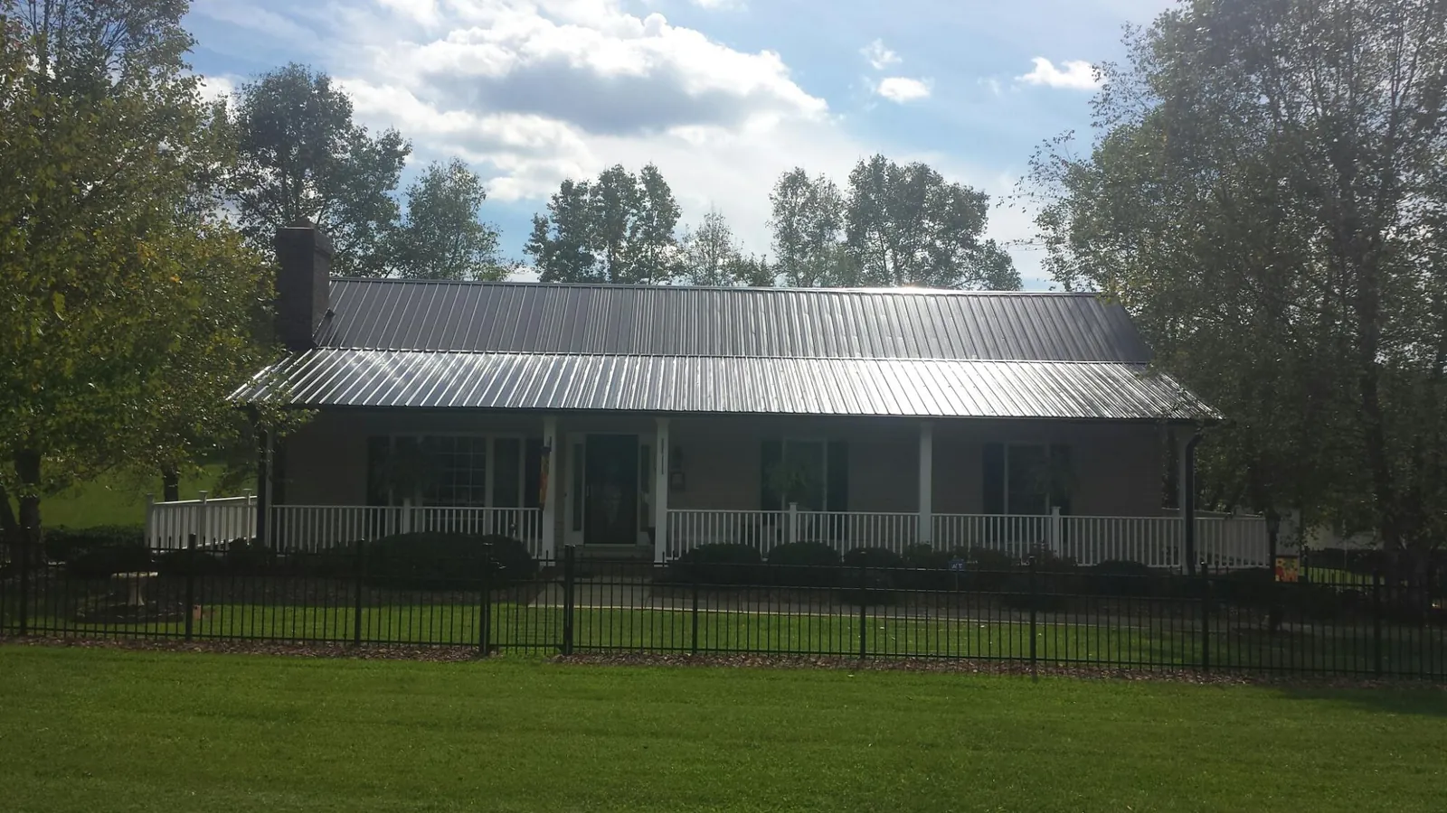 Gray metal roof on a brick ranch with a full width front porch — Gutter Guard Installation work by our crew in Toronto