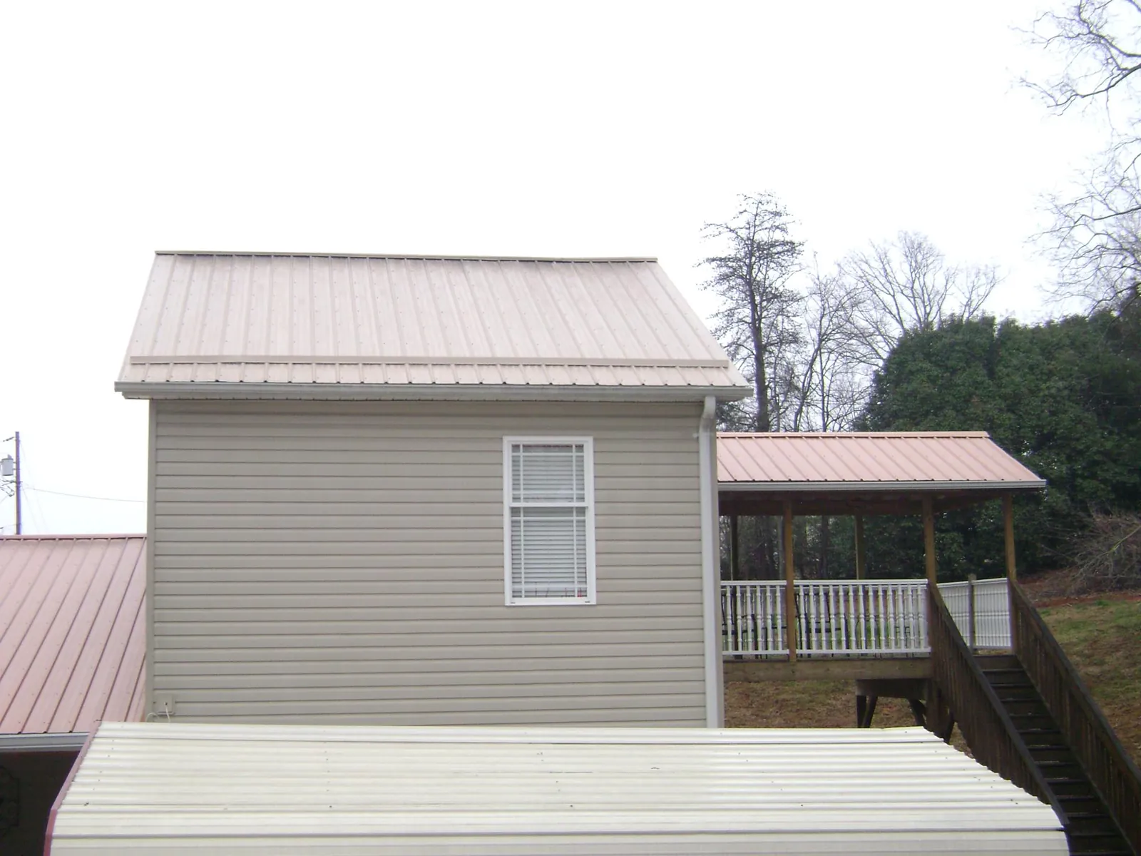 Tan metal roofs on a two story addition and attached porch, from a Roof Replacement job in Toronto
