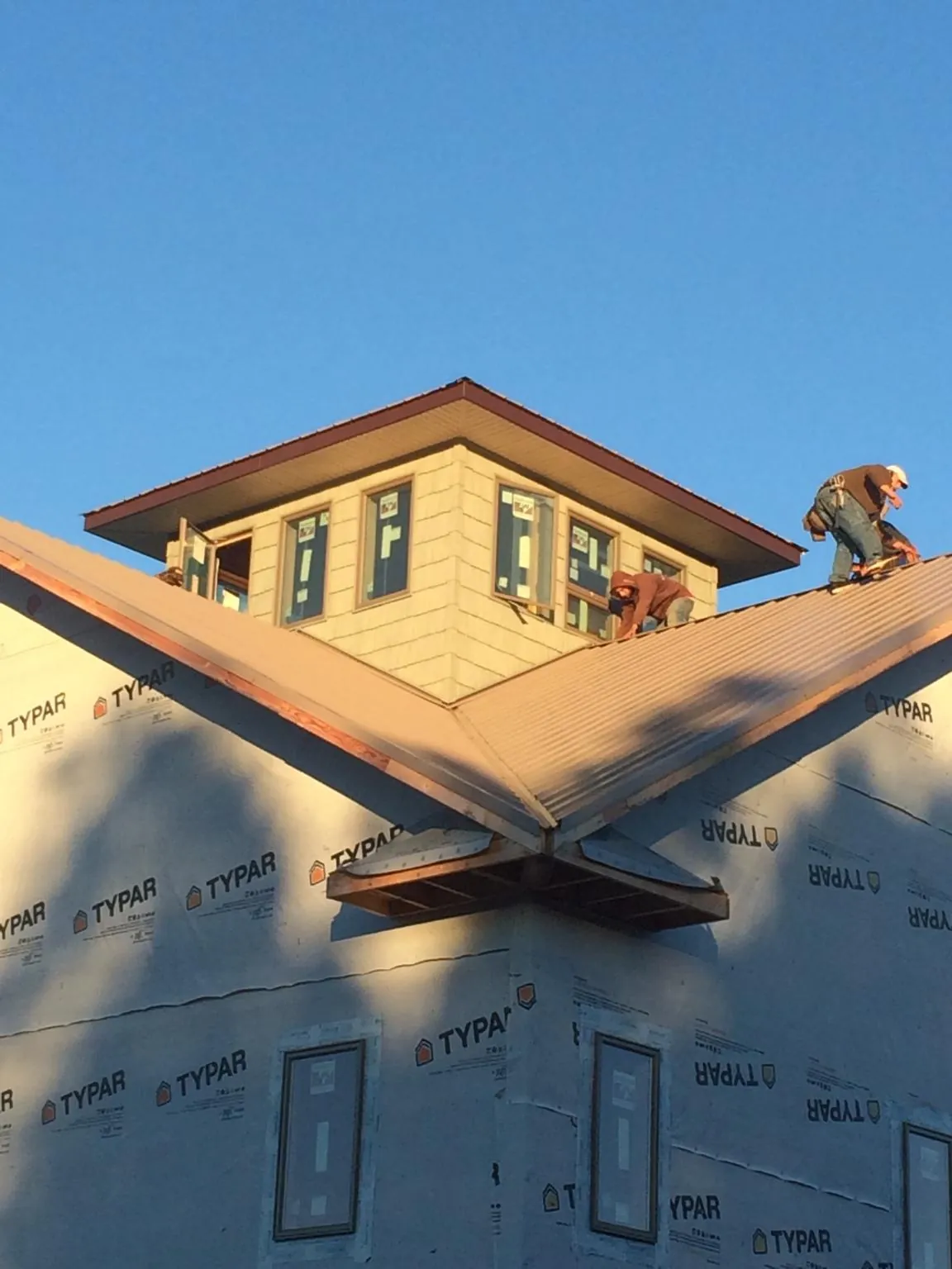 Roofers working around a rooftop cupola on a new metal roof at sunset — Roof Waterproofing in Toronto by Roofing Brothers